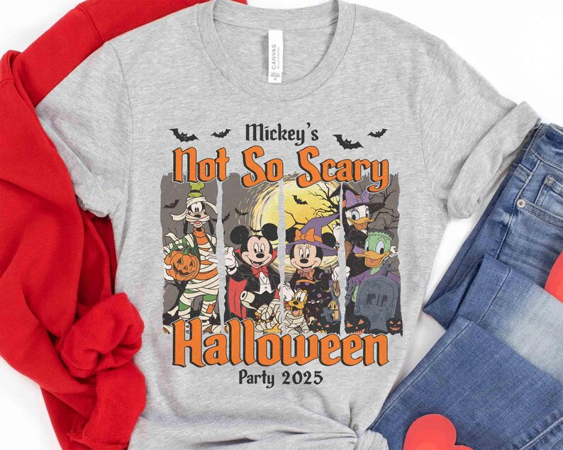 May include: A gray t-shirt featuring a Halloween design with Disney characters. The design includes Mickey Mouse, Minnie Mouse, Donald Duck, and Goofy in Halloween costumes. The text reads "Mickey's Not So Scary Halloween Party 2025".