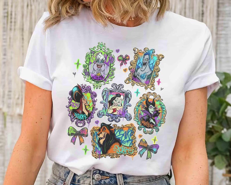 Puede incluir: Camiseta blanca con retratos coloridos de villanos de Disney en marcos ornamentados. Los retratos incluyen personajes como &Uacute;rsula, Jafar y Mal&eacute;fica, con detalles de estilo grafiti y lazos. Un dise&ntilde;o divertido y art&iacute;stico para los fans de Disney.