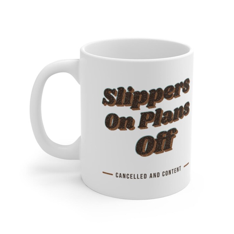 May include: A white ceramic mug featuring the dark brown text Slippers On Plans Off in a bold, retro-inspired font. Below the main text, a smaller line reads CANCELLED AND CONTENT in a simple sans-serif font, flanked by two horizontal brown lines.