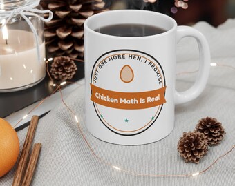 May include: A white ceramic mug featuring a circular graphic with a brown egg icon, the text "JUST ONE MORE HEN, I PROMISE" in black, and a brown banner across the center with the white text "Chicken Math Is Real" and small teal stars.