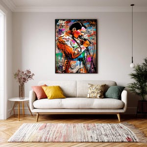 May include: A vibrant pop art style portrait of a singer in an orange jacket, holding a microphone. The artwork features graffiti-style elements with splashes of color, including red, blue, and green. The image is framed and displayed above a white sofa.
