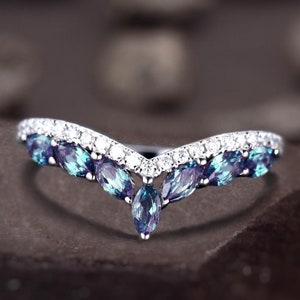 May include: A silver ring with a V-shaped band set with blue and purple gemstones and small clear diamonds.