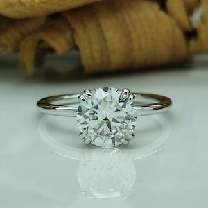 May include: A silver engagement ring with a large, round, clear diamond.