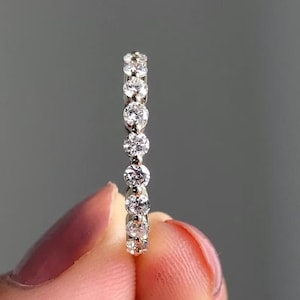May include: A delicate gold band with a row of small, round diamonds.