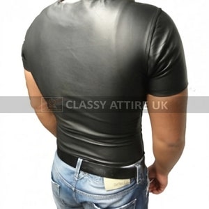 May include: A black, short-sleeved shirt with a shiny, leather-like appearance. The shirt is form-fitting and has a crew neck. The image also shows blue jeans and a black belt. The text "Classy Attire UK" is visible.