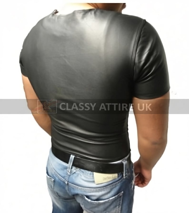 May include: A black, short-sleeved shirt with a shiny, leather-like appearance. The shirt is form-fitting and has a crew neck. The image also shows blue jeans and a black belt. The text "Classy Attire UK" is visible.