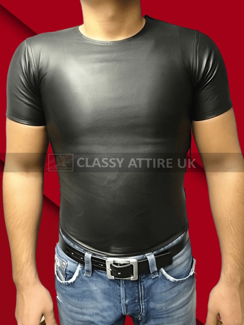 May include: A black, short-sleeved shirt with a crew neck. The shirt is made of a shiny material and is paired with blue jeans and a black belt with a silver buckle. The text "CLASSY ATTIRE UK" is visible.