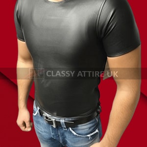 May include: Black short-sleeved t-shirt with a crew neck. The shirt is made of a shiny material and is paired with blue jeans and a black belt. The text "CLASSY ATTIRE UK" is visible.