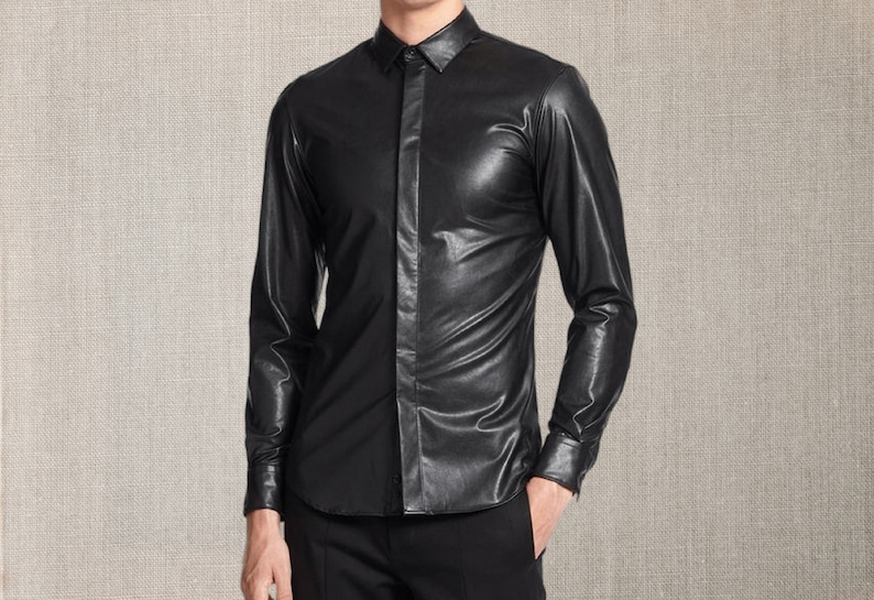 Pu&ograve; includere: Una camicia di pelle nera con maniche lunghe e bottoni. La camicia ha un colletto classico e viene indossata con pantaloni neri. Il materiale ha una leggera lucentezza e l'aspetto generale &egrave; elegante e moderno.