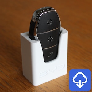 May include: White 3D printed key holder with a black car key inside. The key has three buttons: a power button, a lock button, and an unlock button.