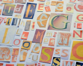 Puede incluir: Una colección de letras recortadas de varios tamaños y fuentes, dispuestas sobre una superficie blanca. Las letras son principalmente de color naranja, amarillo y azul, algunas con fondos estampados. La imagen tiene una estética de collage o álbum de recortes.