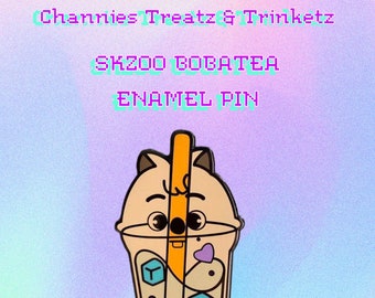 May include: A brown and beige enamel pin featuring a cartoon quokka holding a boba tea cup with a straw. The quokka has a pink heart on its chest and the boba tea cup has purple and blue boba balls and ice cubes. The text "SKZOO BOBATEA ENAMEL PIN" is above the quokka and the text "Quokka" is below the quokka.