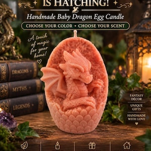 May include: A coral-coloured, oval-shaped candle featuring a sculpted baby dragon emerging from a textured egg shell. The candle has a single wick at the top. Text on the image reads: A LITTLE DRAGON IS HATCHING! Handmade Baby Dragon Egg Candle.