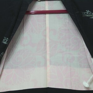 K&ouml;nnte beinhalten: Ein schwarzer Kimono mit einem rosa floralen Musterfutter. Der Kimono hat eine wei&szlig;e Schnur und ein silbernes Design auf dem schwarzen Stoff.