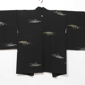 K&ouml;nnte beinhalten: Ein schwarzer japanischer Kimono mit einem traditionellen Design aus wei&szlig;en und goldenen Wolken. Der Kimono hat einen schlichten, eleganten Stil und ist perfekt f&uuml;r besondere Anl&auml;sse.