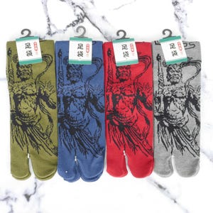 Può includere: Quattro paia di calze tabi con un design a punta divisa. Le calze sono di colore verde, blu, rosso e grigio. Ogni calza presenta una stampa grafica in bianco e nero di un demone giapponese.