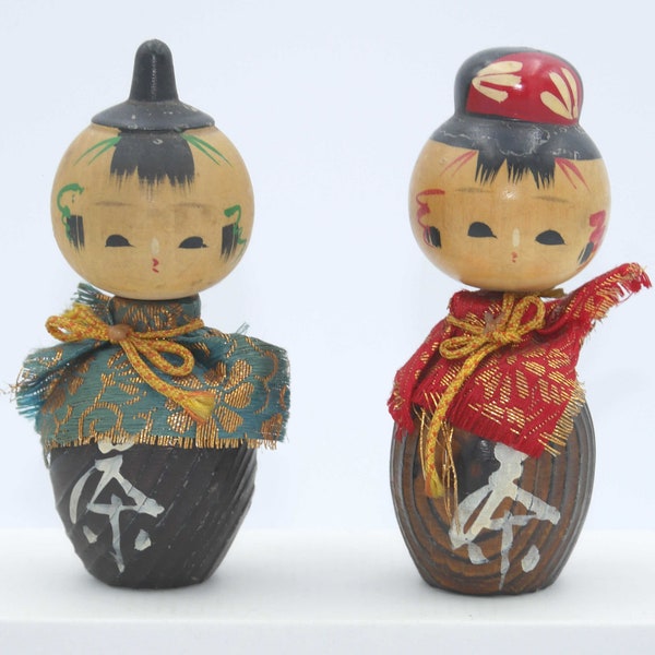 Couple de poupée Kokeshi japonaises créatives Sosaku représentant un couple avec un kanji blanc et du tissu bleu et rouge