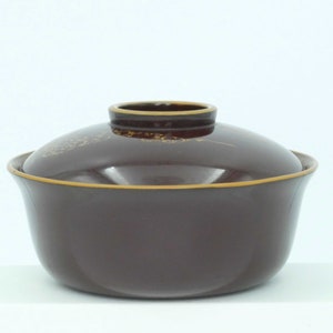 May include: A dark brown ceramic bowl with a lid. The bowl has a gold rim and a subtle gold design. The lid has a gold rim and a gold design.