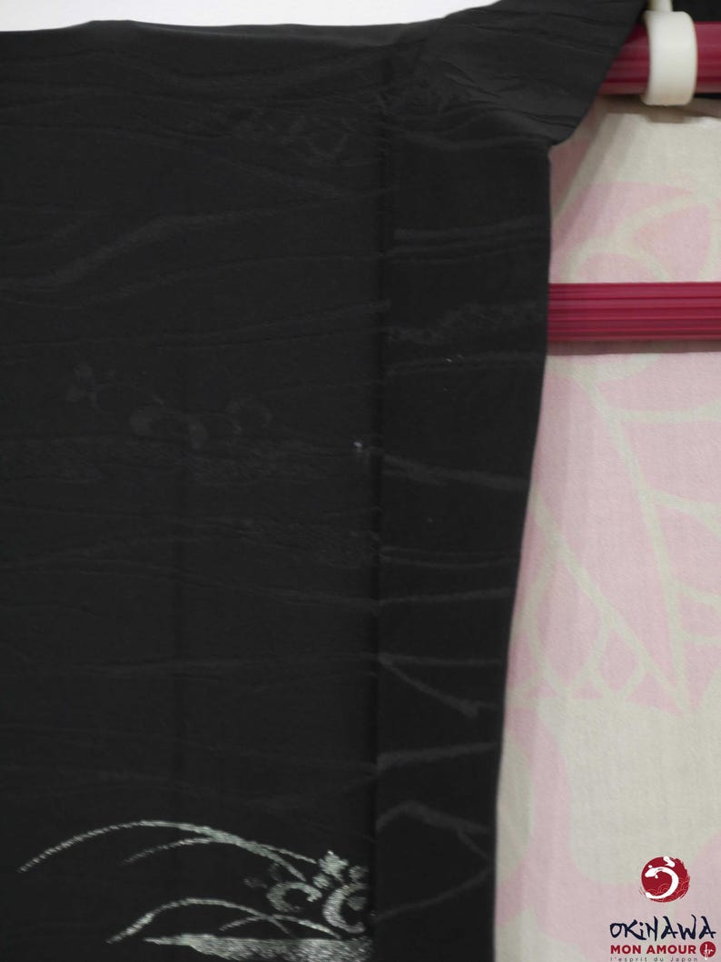 K&ouml;nnte beinhalten: Schwarzer Kimono mit silbernem Blumendesign. Der Kimono h&auml;ngt an einem Kleiderb&uuml;gel.