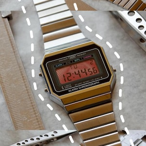 May include: Silver-toned digital watch with a rectangular face displaying the time 12:44:56. The watch has a metal band and features the text "WATER WR RESIST" and "ALARM CHRONOGRAPH". Other tools are also visible.
