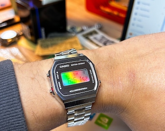 Mirror Chameleon: reloj modificado basado en el Casio A168, con carátula de espejo con cambio de color y brazalete metálico con peso. Modificación digital Casio personalizada.