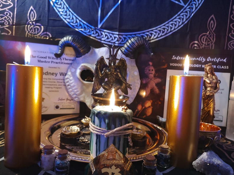 May include: A gold metal tray with candles, a small statue of a demon, and various bottles and jars. The tray is on a dark surface with a black and blue patterned fabric in the background. The text on the certificate reads "Internationally Certified Vodou Theology Master Class".
