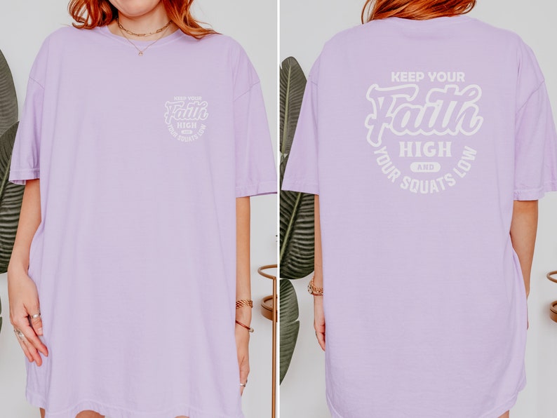 May include: A lavender oversized t-shirt with the text "Keep Your Faith High And Your Squats Low" printed on the back in white. The front of the shirt has a smaller version of the text printed on the left side of the chest.