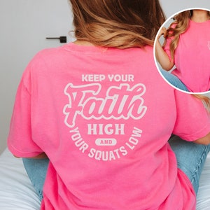May include: Pink t-shirt with a white graphic that says "Keep Your Faith High and Your Squats Low".