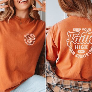 May include: Orange t-shirt with a white graphic that says "Keep your faith high and your squats low".