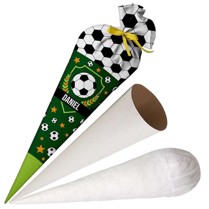 May include: A conical school cone featuring a soccer ball pattern, a green section with small soccer balls and stars, and the name DANIEL printed on a black banner. The top is tied with a yellow ribbon. Two plain white conical inserts are also shown.
