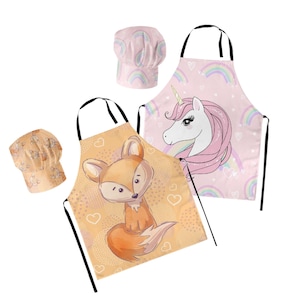 Può includere: Due grembiuli da cucina colorati con cappelli da chef abbinati. Un grembiule presenta uno sfondo rosa con un arcobaleno e un unicorno, mentre l'altro ha uno sfondo giallo con una volpe.
