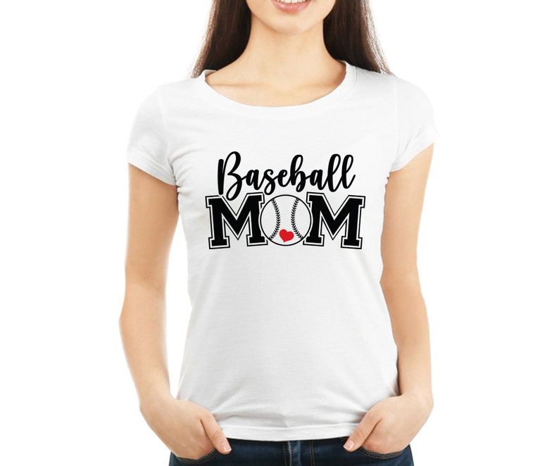 May include: White t-shirt with the text "Baseball MOM" in black script and block letters. A baseball graphic with a red heart replaces the "O" in MOM. The shirt is a crew neck style.