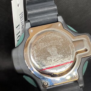 K&ouml;nnte beinhalten: Schwarze Uhr mit schwarzem Armband und silbernem R&uuml;cken. Die Uhr hat einen gr&uuml;nen Akzent an der Seite. Auf der R&uuml;ckseite der Uhr stehen die Worte "FIELD & STREAM" und ein Adlerbild. Ein wei&szlig;es Etikett ist angebracht.