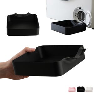 Könnte beinhalten: Eine rechteckige schwarze Kunststoff-Auffangschale mit einer geschwungenen Aussparung an einer Seite, die unter die Filterklappe einer Waschmaschine passt. Die Schale hat glatte Wände und einen flachen Boden und wird aus verschiedenen Perspektiven gezeigt.