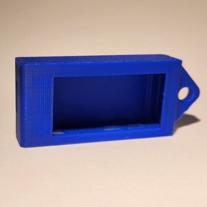 May include: A small, blue plastic case with a rectangular opening and a loop on the side. The case is designed to hold a small electronic device.