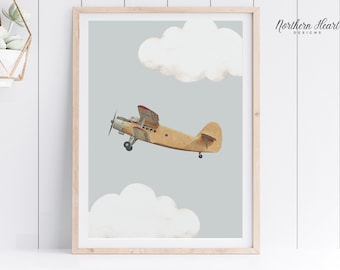 May include: A framed print featuring a vintage biplane in flight against a light blue sky with two fluffy white clouds. The biplane is tan with red accents. The print is in a light wood frame.