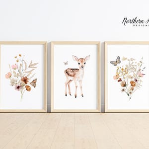 May include: Three framed watercolour art prints. The prints feature a fawn, floral bouquets, and butterflies. The frames are light wood. The artwork has a soft, neutral colour palette with touches of pink, brown, and yellow. The text "Northern Heart Designs" is in the upper right corner.