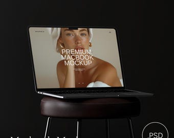 Könnte beinhalten: Ein schwarzer Laptop mit einem weißen Bildschirm, auf dem der Text "PREMIUM MACBOOK MOCKUP" und ein Foto einer Frau zu sehen sind. Der Laptop steht auf einem braunen Lederhocker.