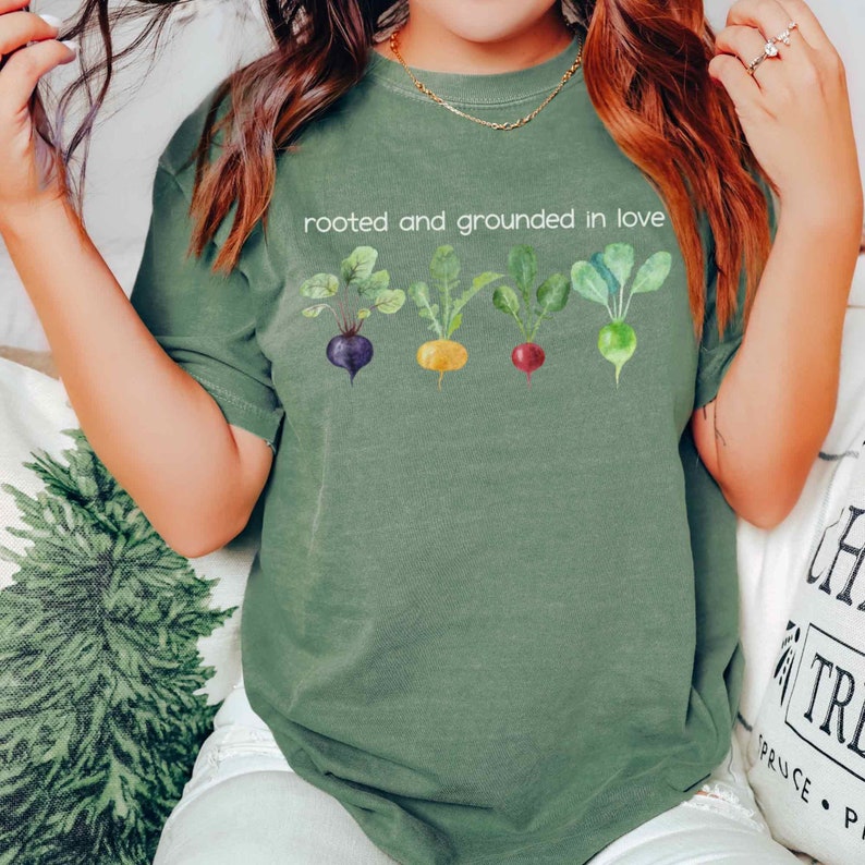May include: A green t-shirt with the text "rooted and grounded in love" and a graphic of four different colored root vegetables.