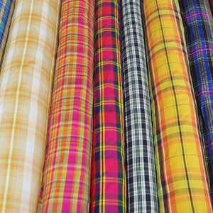 Op de afbeelding: Assortiment van geruite stofrollen in verschillende kleuren, waaronder groen, geel, roze, rood, blauw en zwart.