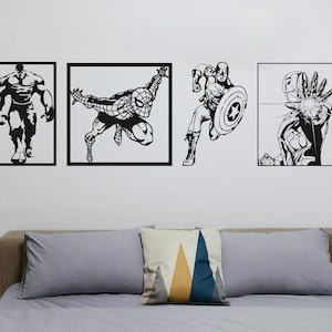 May include: Four black and white wall decals featuring superhero characters. The decals are framed in black and are arranged in a row on a white wall. The characters are Hulk, Spiderman, Captain America, and Iron Man.