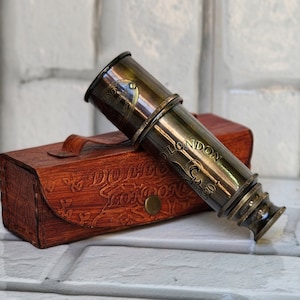 Puede incluir: Un telescopio de latón con una funda de cuero. El telescopio está grabado con las palabras "Dollond London" y "C. 1920".