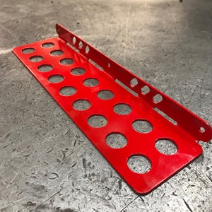 May include: A red metal tool organizer with multiple circular cutouts. The organizer is designed to hold tools and is made of durable metal.