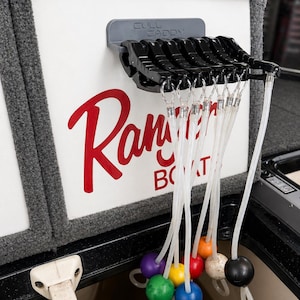 May include: A black Cull Caddy fishing accessory mounted on a white surface with the red Ranger Boats logo. Attached are multiple clear tubes with colorful, spherical floats. The floats are purple, green, yellow, blue, red, orange, beige, and black.