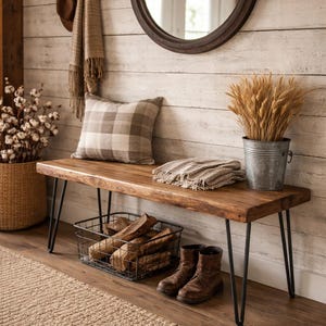 May include: A rustic entryway scene featuring a wooden bench with black hairpin legs. A plaid pillow and a folded blanket rest on the bench. A metal basket holds firewood, and brown boots sit on the floor. A round mirror hangs on the wall.