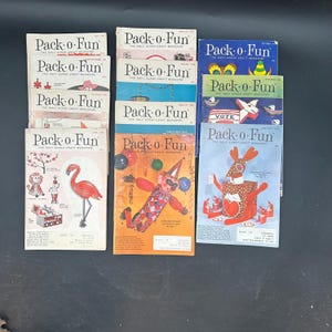 May include: A collection of vintage "Pack-o-Fun" magazines. The covers feature colorful illustrations of crafts, clowns, animals, and holiday themes. The magazines are stacked on a dark surface, showcasing their retro design and the magazine's title.
