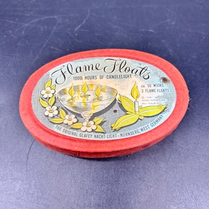 May include: Red oval tin container with a white and blue label. The label reads "Flame Floats 1000 Hours of Candlelight ca. 50 Wicks 3 Flame Floats © 1958 Holen Imports, Inc. New York, N.Y. The Original Glafey Nacht-Licht Nürnberg, West Germany".