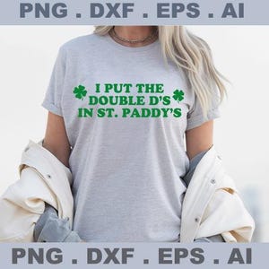 May include: A light gray t-shirt with the text "I PUT THE DOUBLE D'S IN ST. PADDY'S" in green, along with green shamrock graphics. The shirt is a casual style.