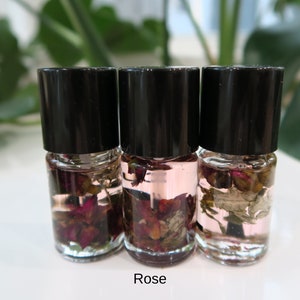 May include: Three small glass bottles with black lids filled with clear liquid and dried rose petals. The bottles are labeled "Rose".