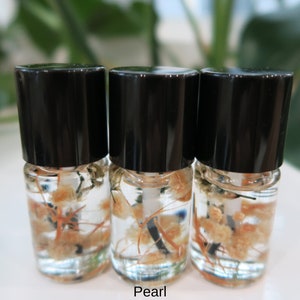 May include: Three small glass bottles with black caps filled with a clear liquid and dried flowers. The bottles are labeled "Pearl".